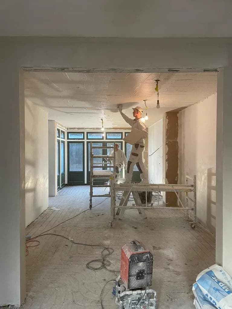 Stukadoor op een rolsteiger aan het werk aan een plafond