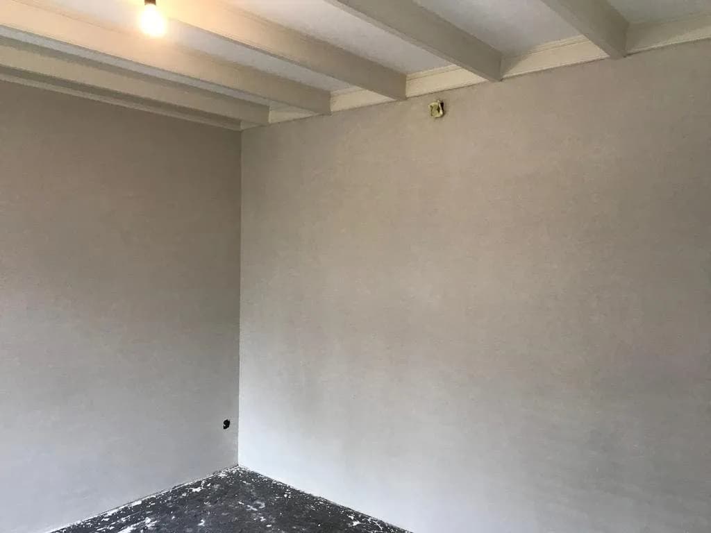 Kamer met glad pleisterwerk op de wanden onder een balkenplafond
